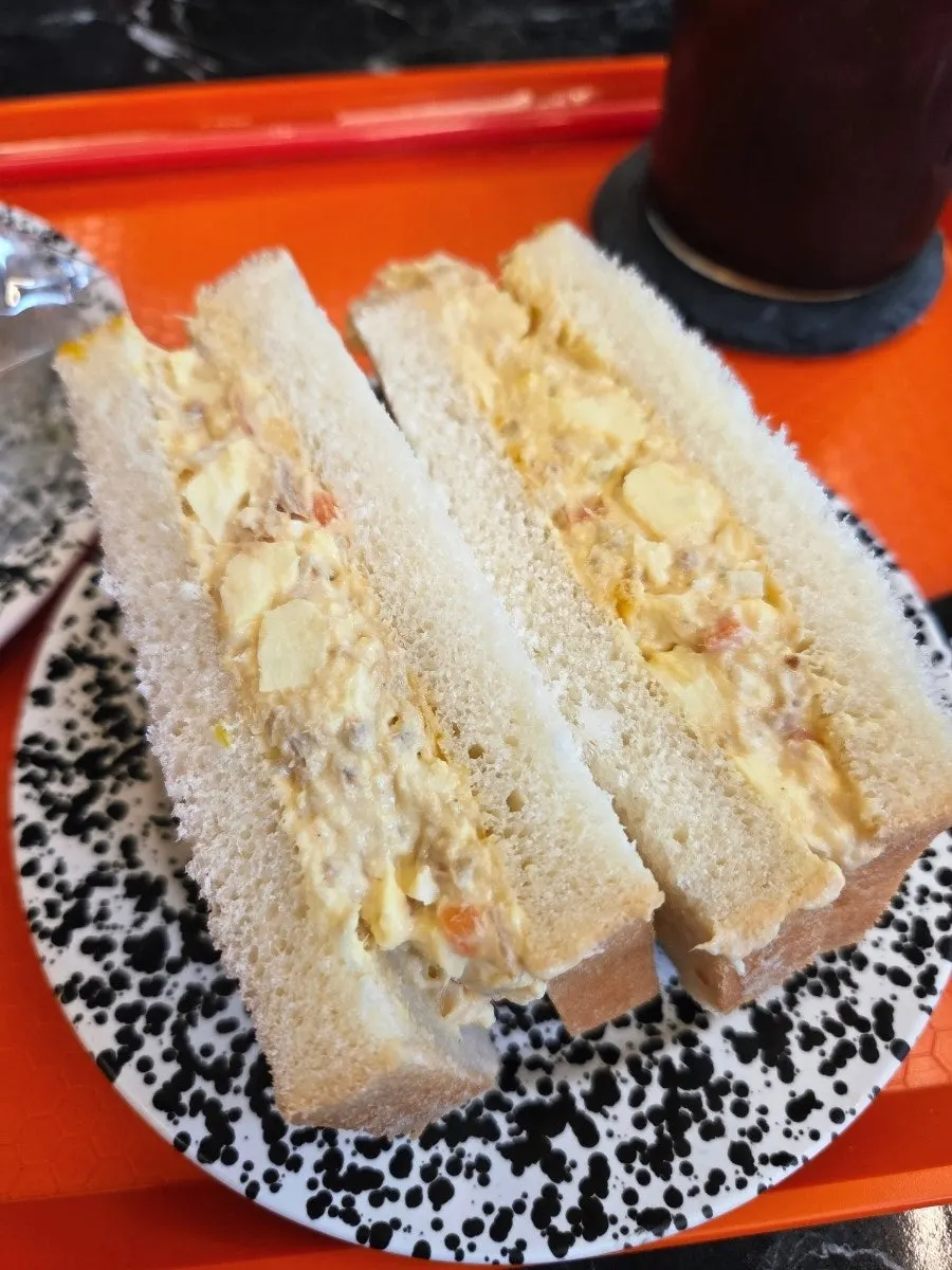 Cross-section of the club sandwich full of lettuce, ham, and tomato