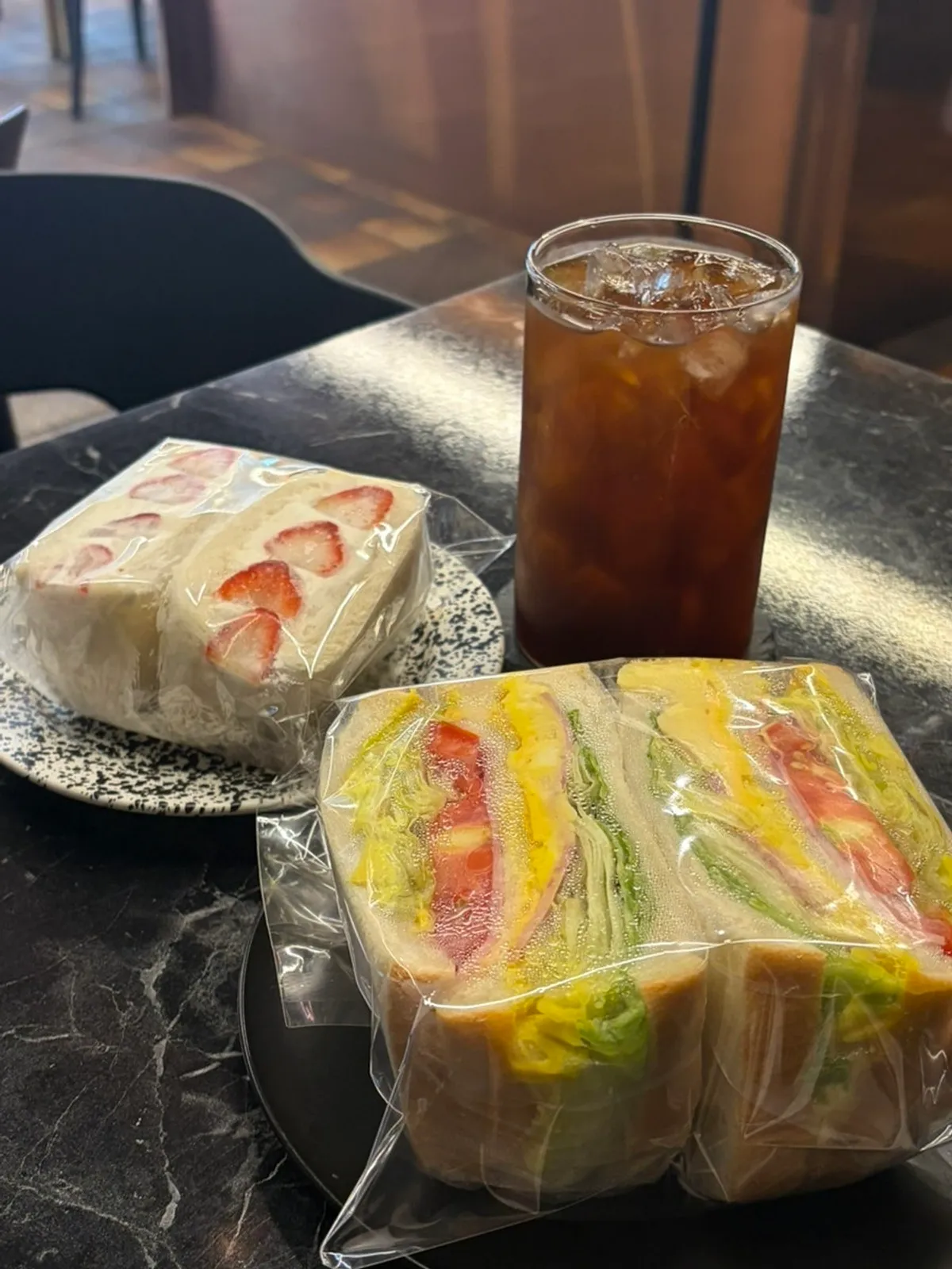 Club sandwich, strawberry sando, and americano set on the table