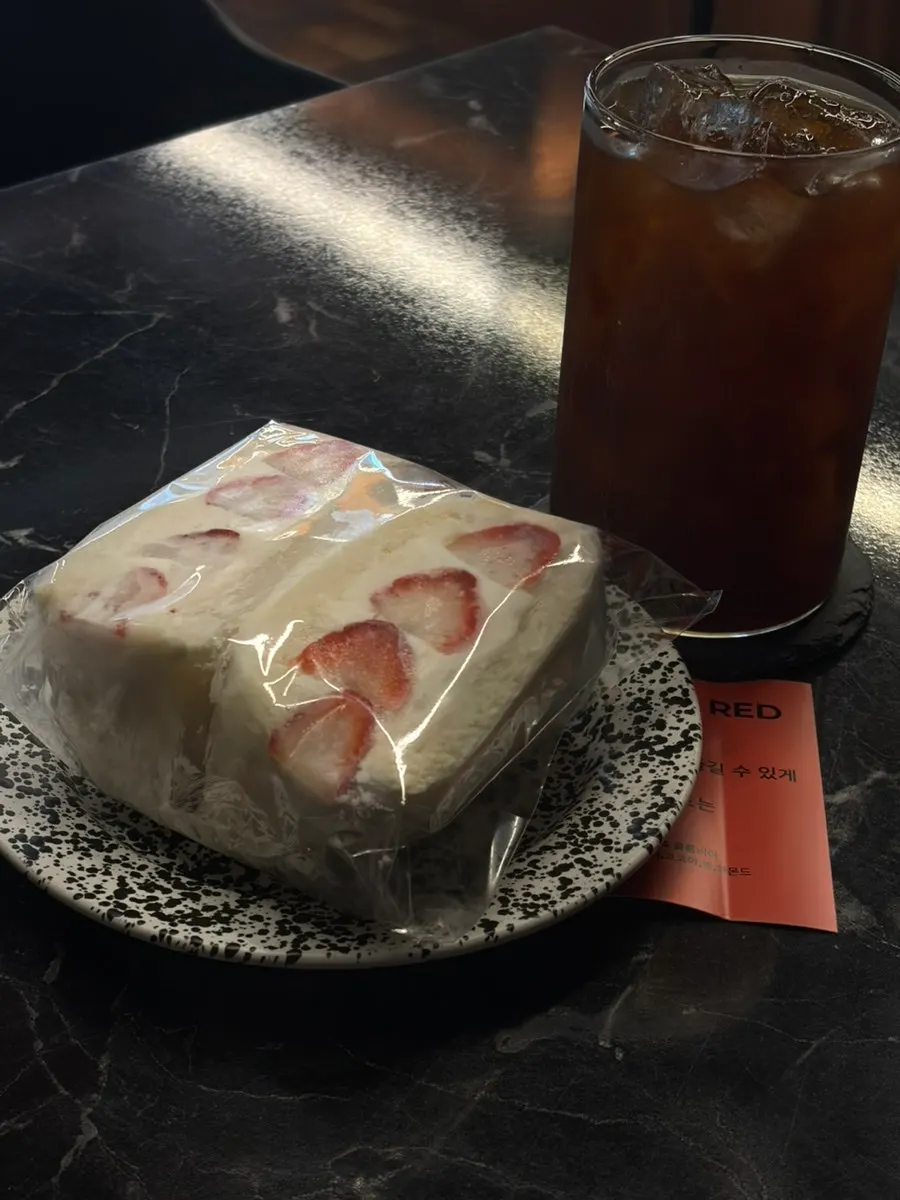 Strawberry sando packed with strawberries next to an americano