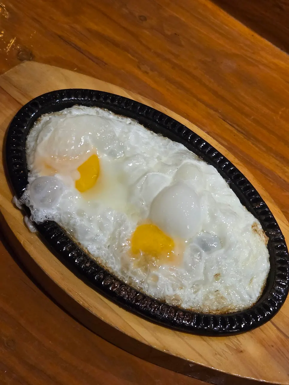 Two fried eggs served as the basic side dish on a hot plate