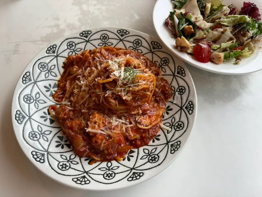 A table setting with spicy beef brisket tomato pasta and ricotta cheese salad