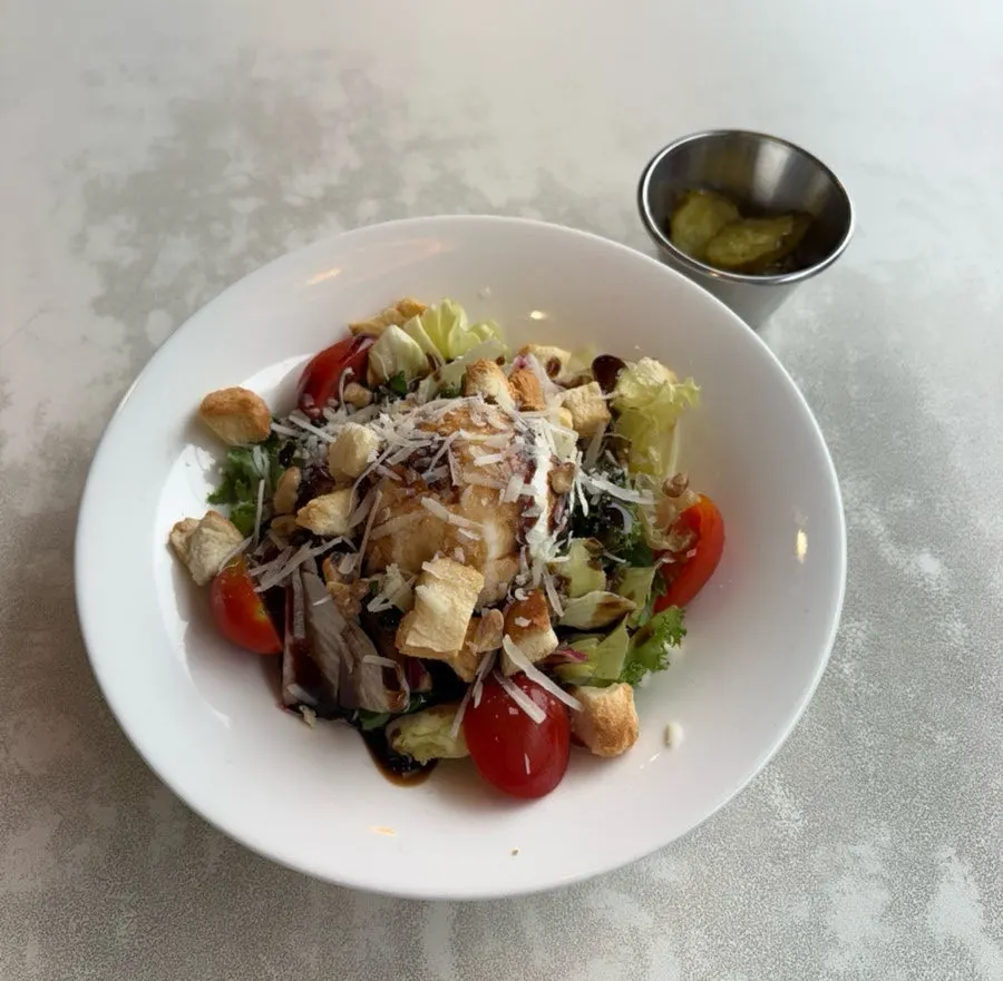 A salad topped with fresh vegetables and ricotta cheese