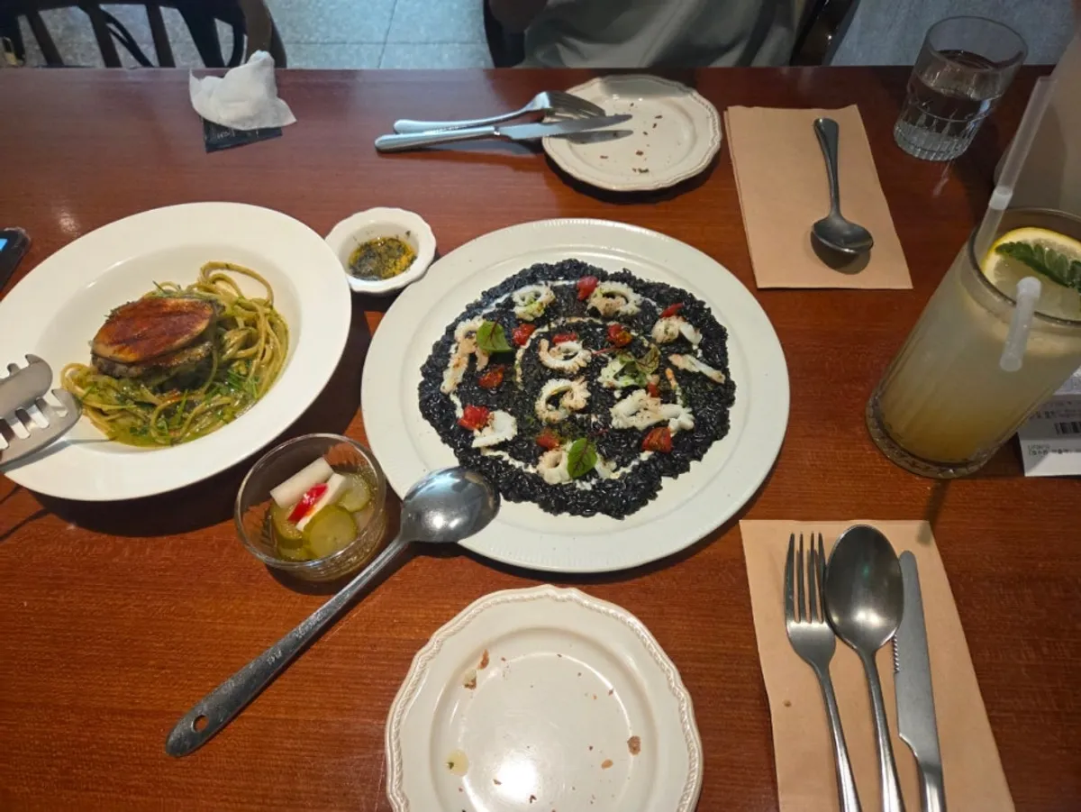 Table with squid ink risotto and abalone gonad pasta