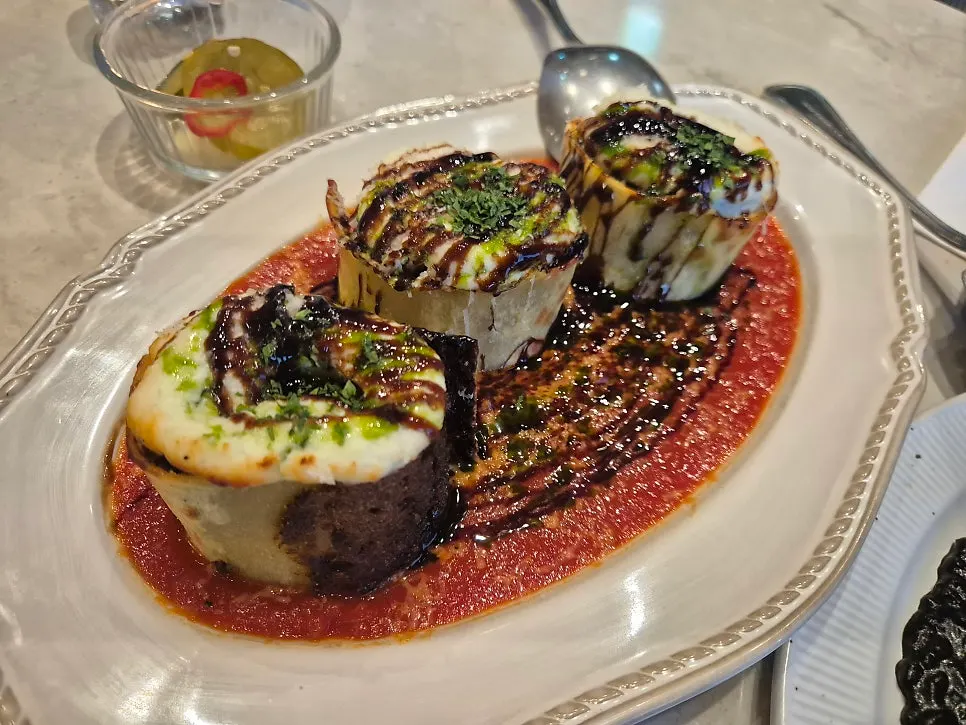 A plate of squid ink risotto topped with tomato