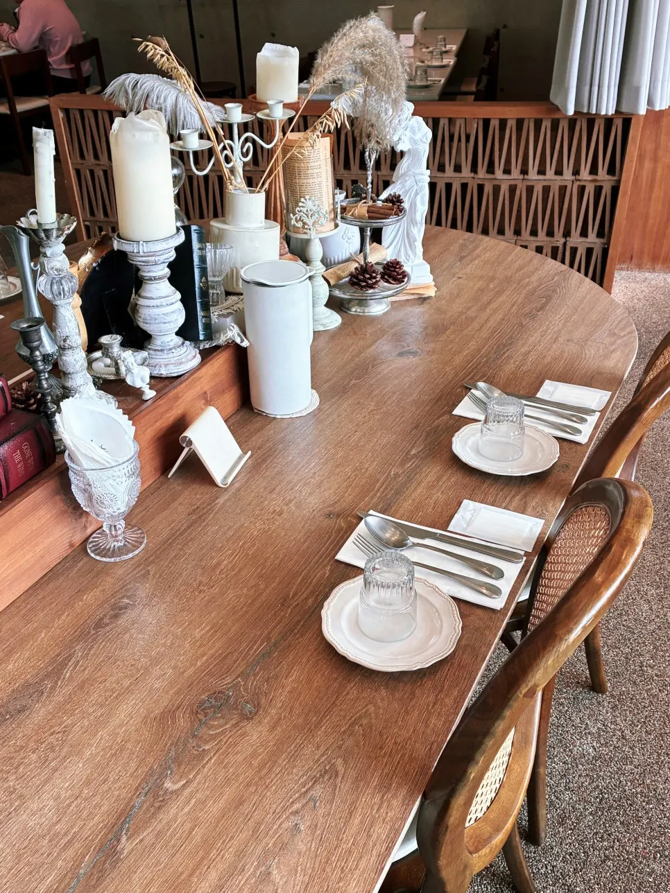 Dining hall with rattan chairs and open kitchen visible