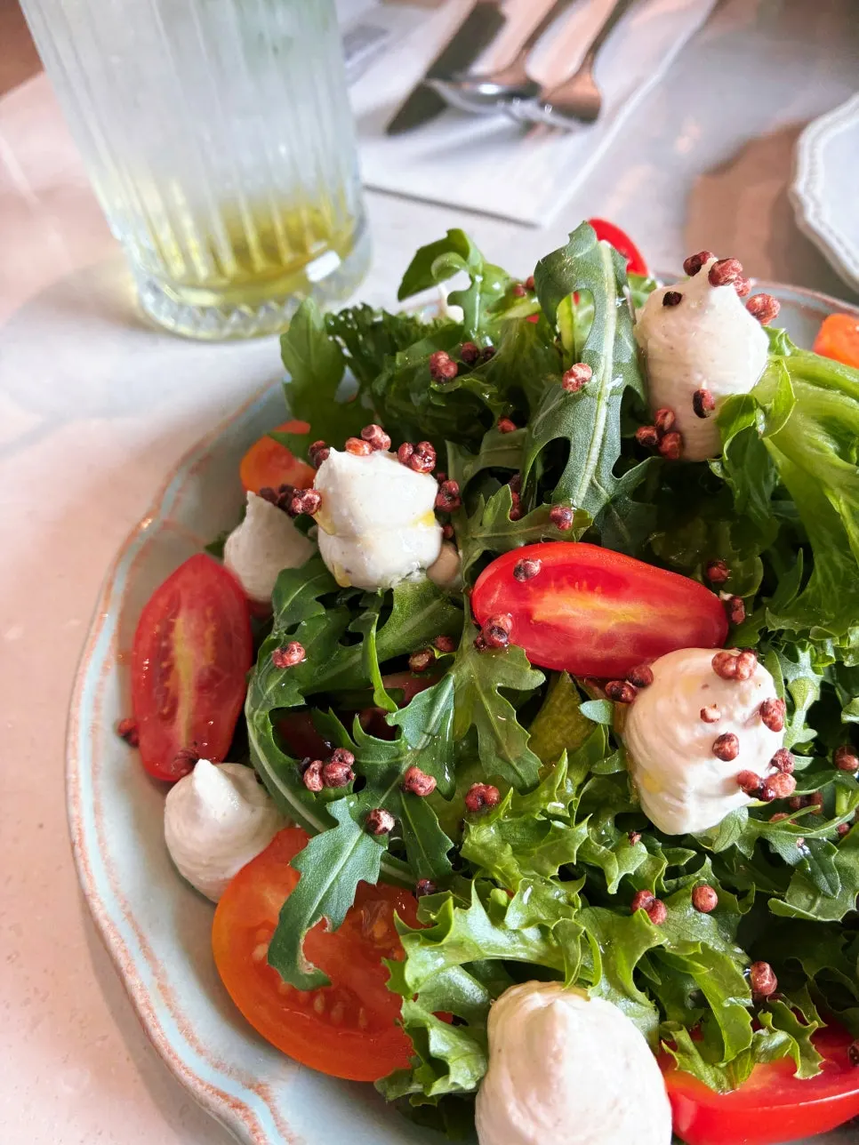 Pine nut caprese topped with tomatoes and arugula