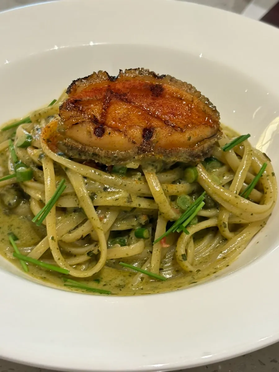 Close-up of geou cream pasta topped with abalone garnish
