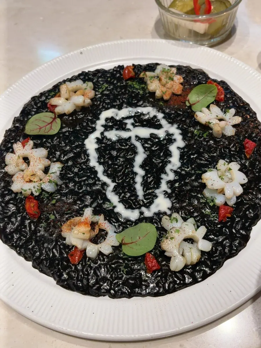 Close-up of squid ink risotto topped with squid
