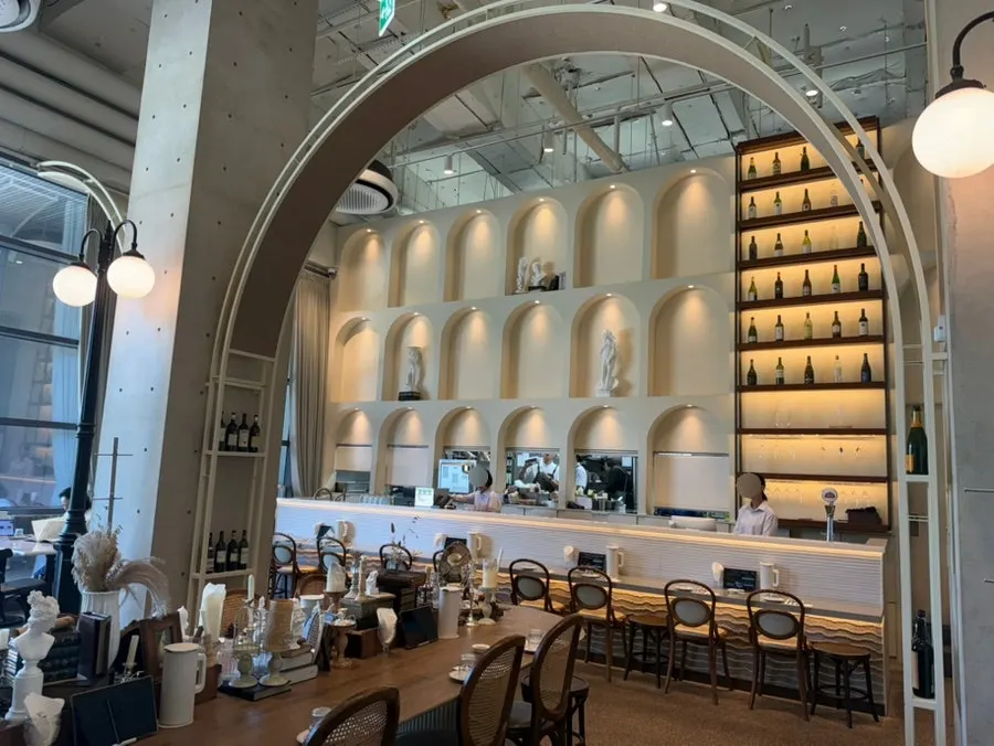 Shelves lined with wine bottles under an exposed concrete ceiling