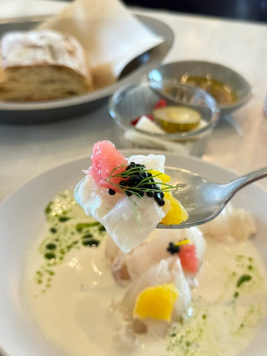 A piece of flounder carpaccio topped with dill