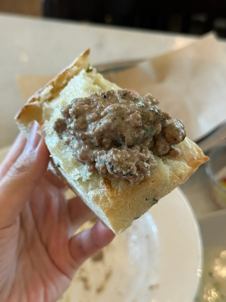 A bite of bread topped with ragu sauce
