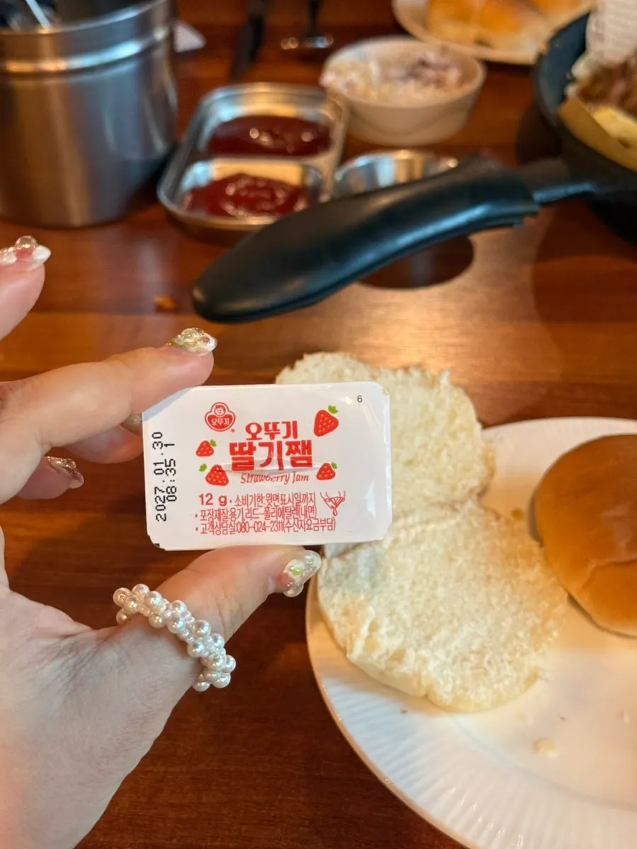 Spreading strawberry jam on a morning roll