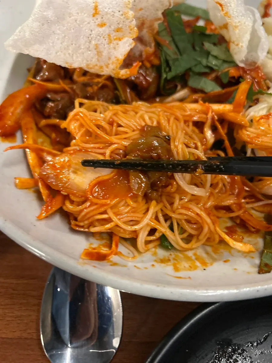 Whelk and vegetables piled on crushed fried rice paper