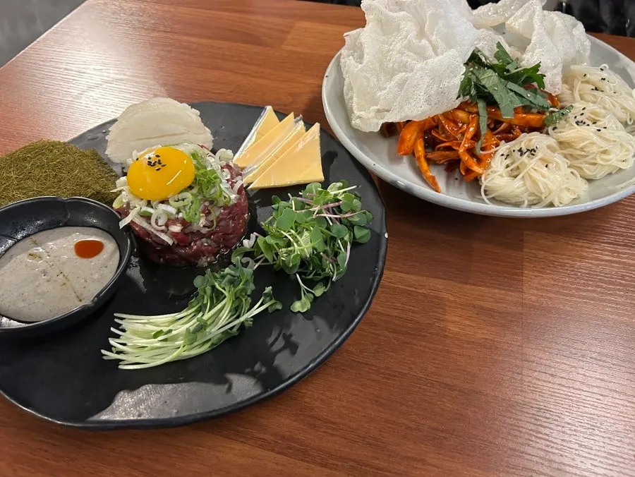 A bite of yukhoe topped with gamtae, pear, and cheese