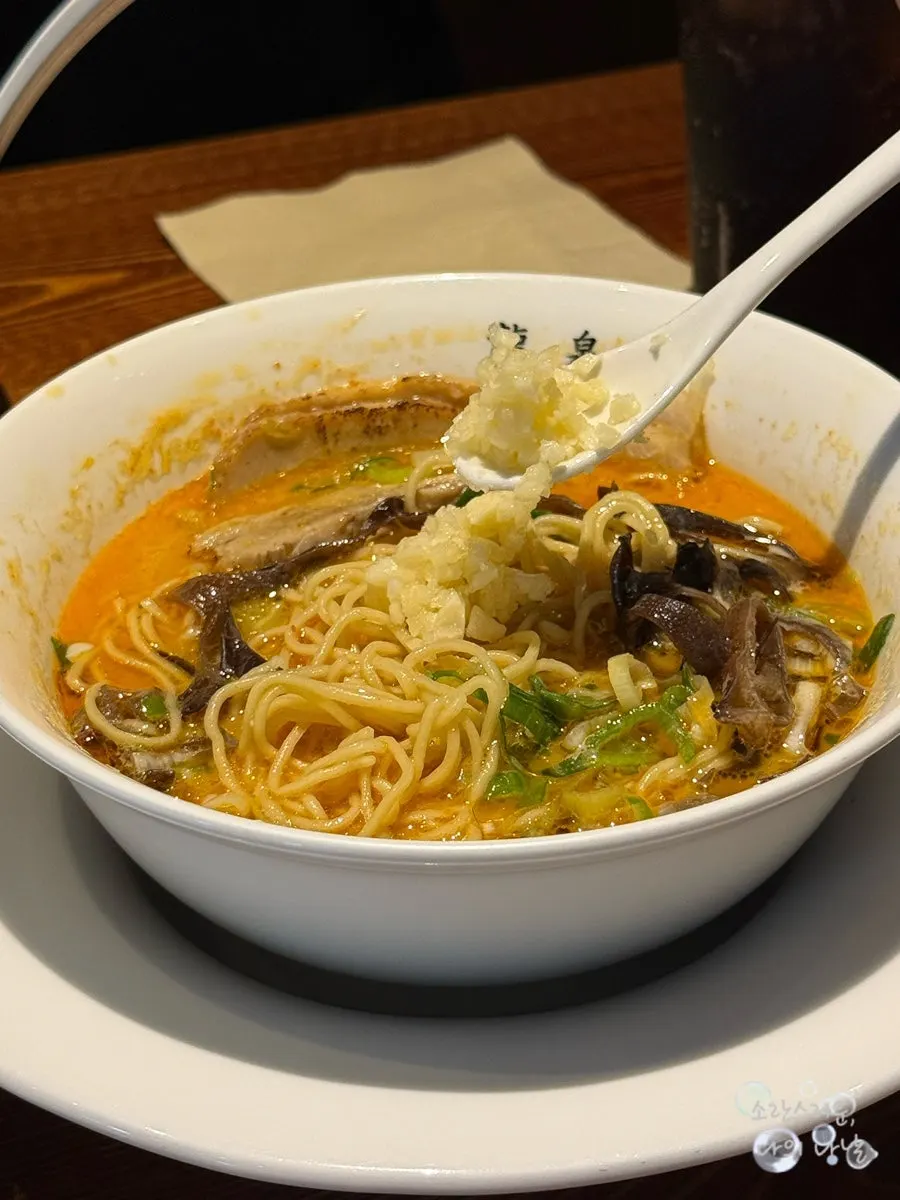 Adding pepper and minced garlic to the ramen broth