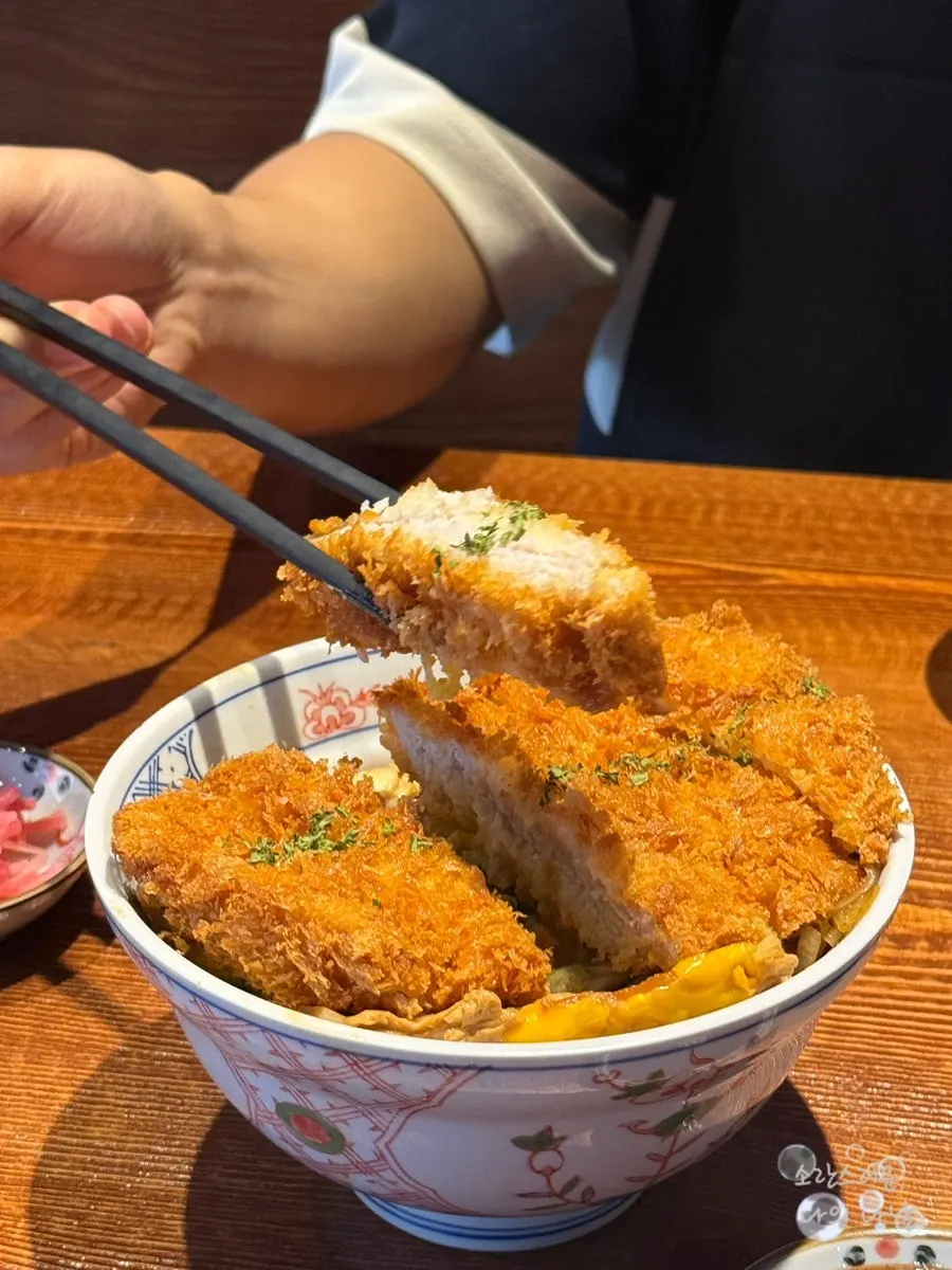 A piece of katsudon pork cutlet dipped in tonkatsu sauce