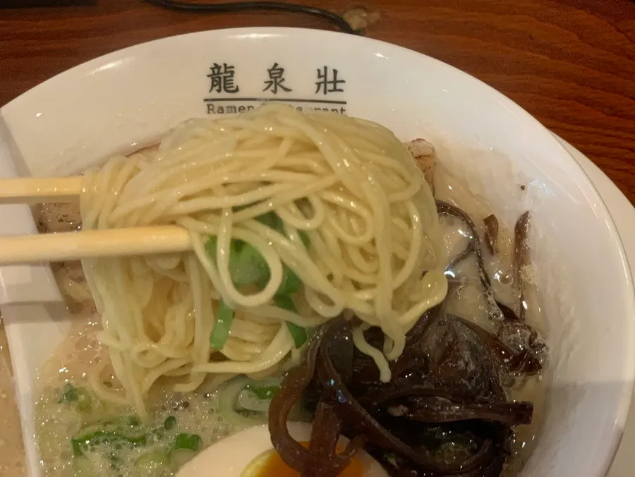 A bite of chashu wrapped in noodles