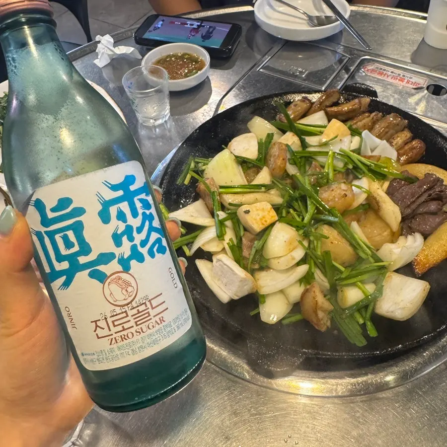 Gopchang on the grill with a glass of soju