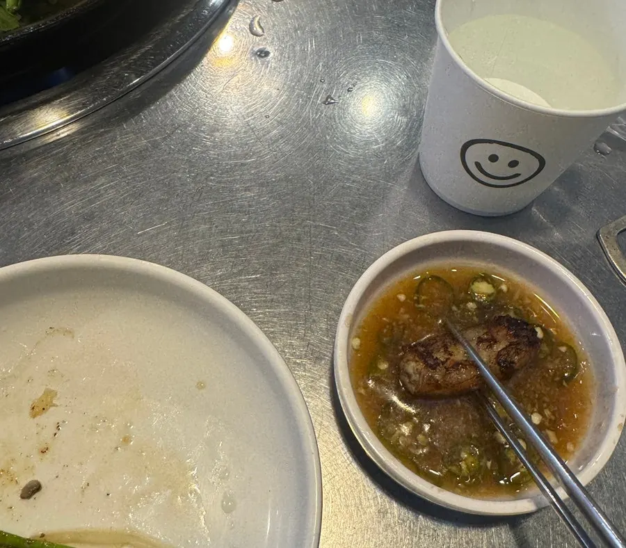 A piece of gopchang topped with sauce and chives