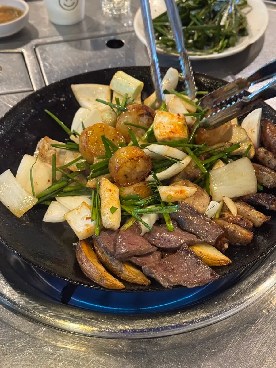 Staff member grilling gopchang on the grill