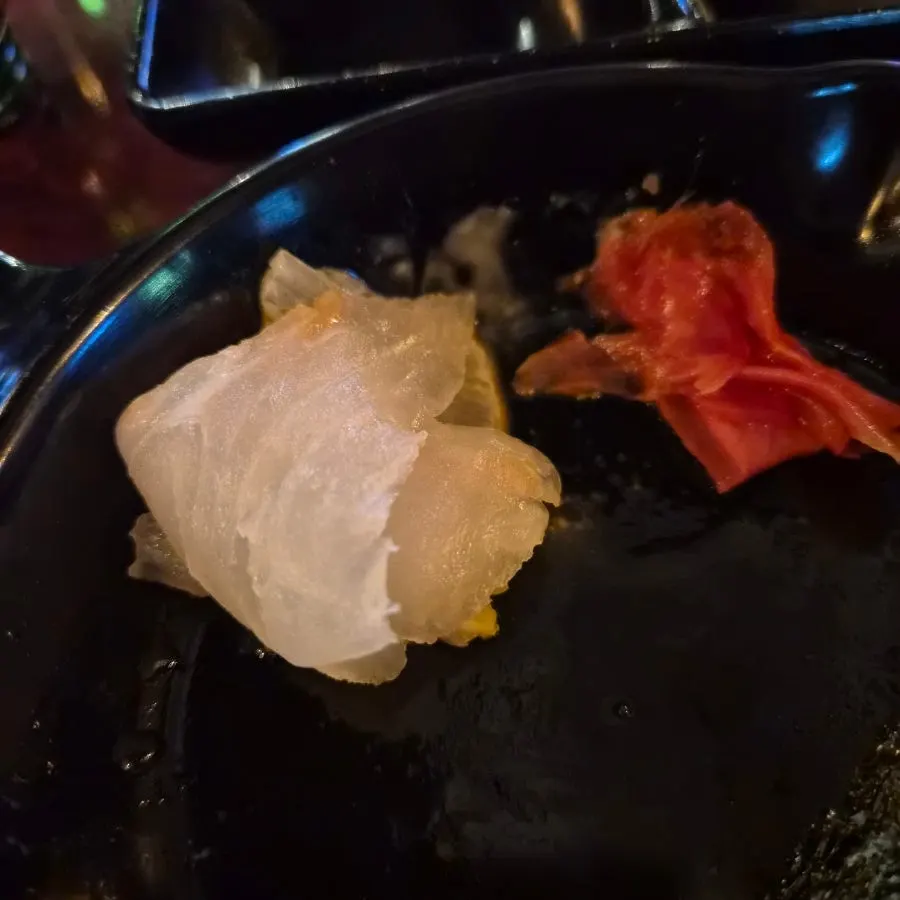 A piece of sashimi topped with ginger