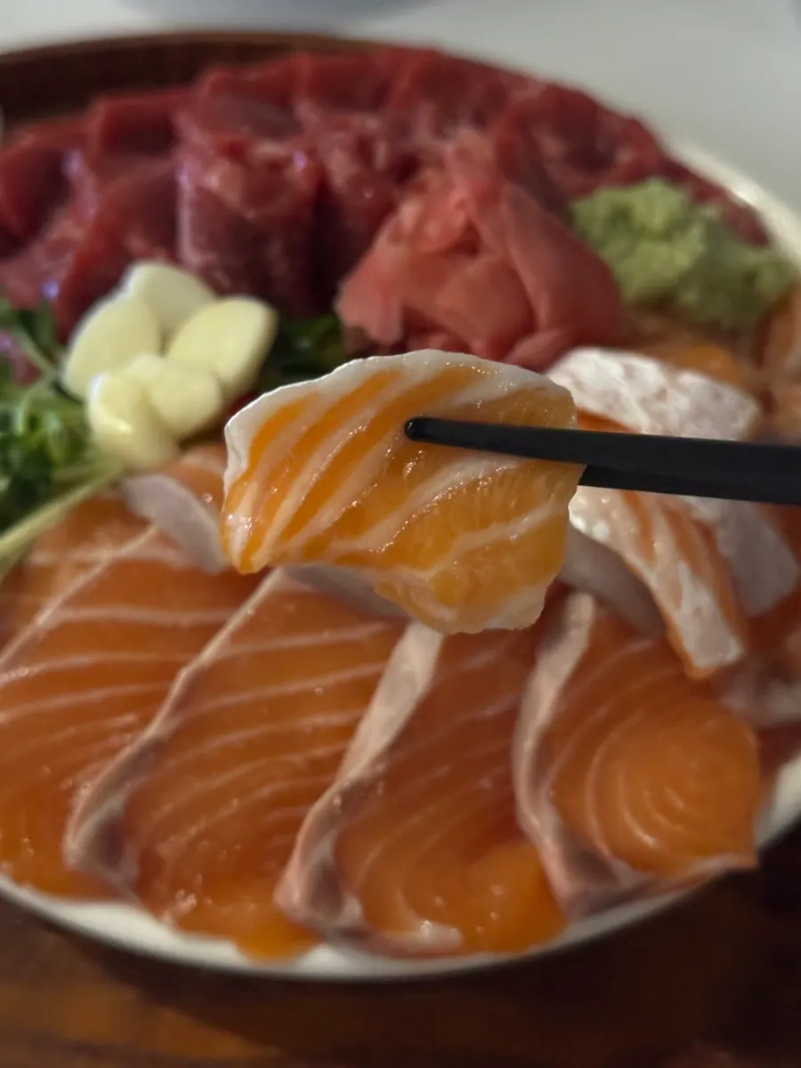 A piece of salmon held with chopsticks
