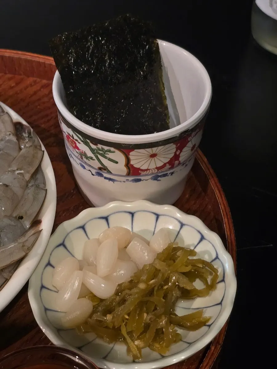 Raw shrimp sashimi served with pickled radish and seaweed