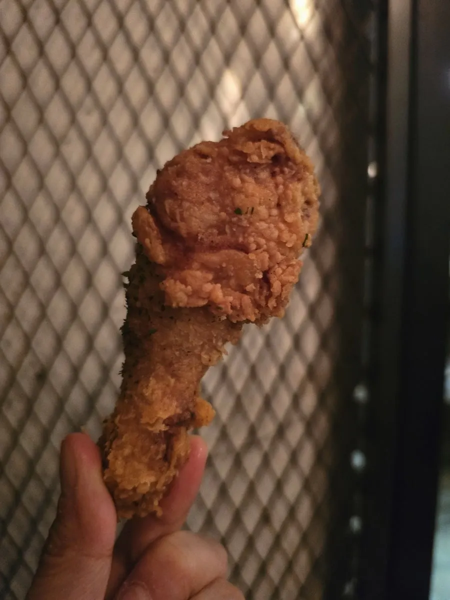 Close-up of a bone-in chicken piece with thin batter