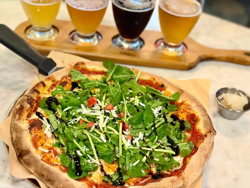 Table with arugula premium pizza and beer