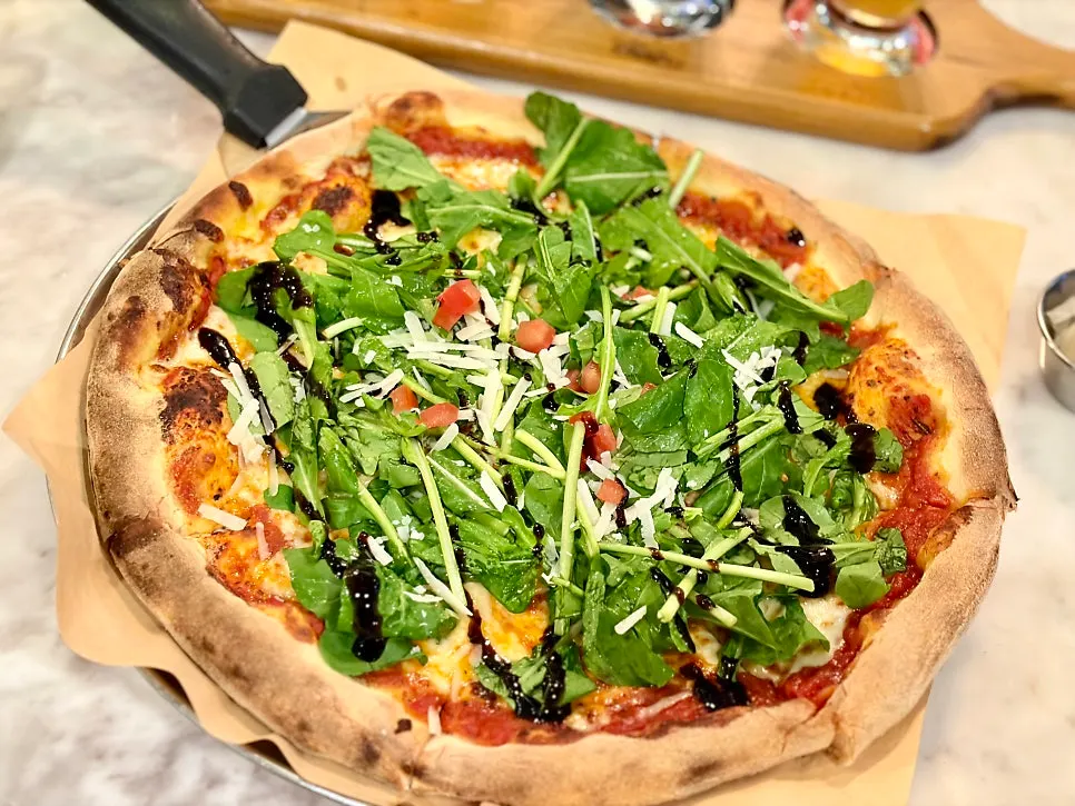 Wood-fired pizza piled high with arugula
