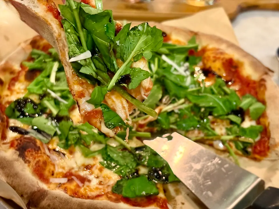Cross-section of arugula pizza with a beer glass