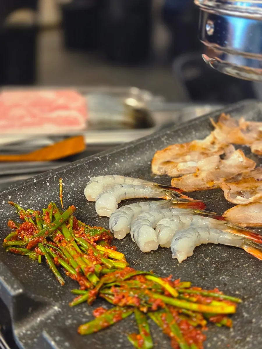Scallion kimchi cooking in the pork fat on the grill