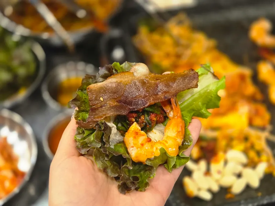 A wrap combining naengsam, shrimp, and scallion kimchi