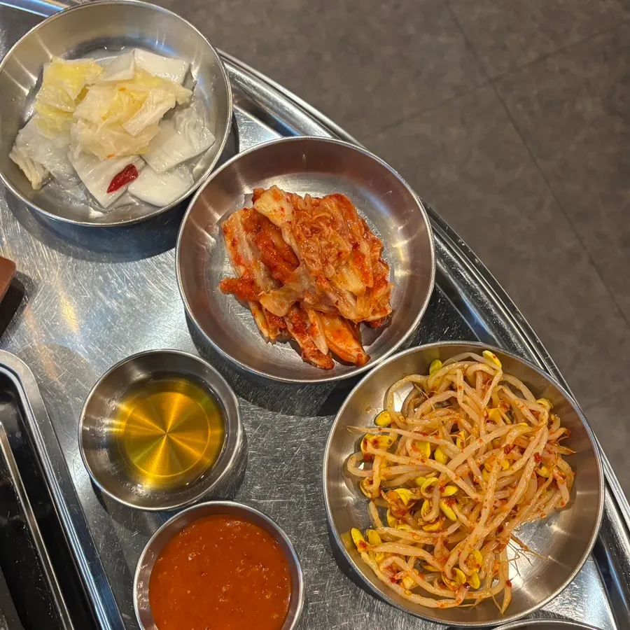Plate of bean sprouts, napa cabbage kimchi, and various sauces