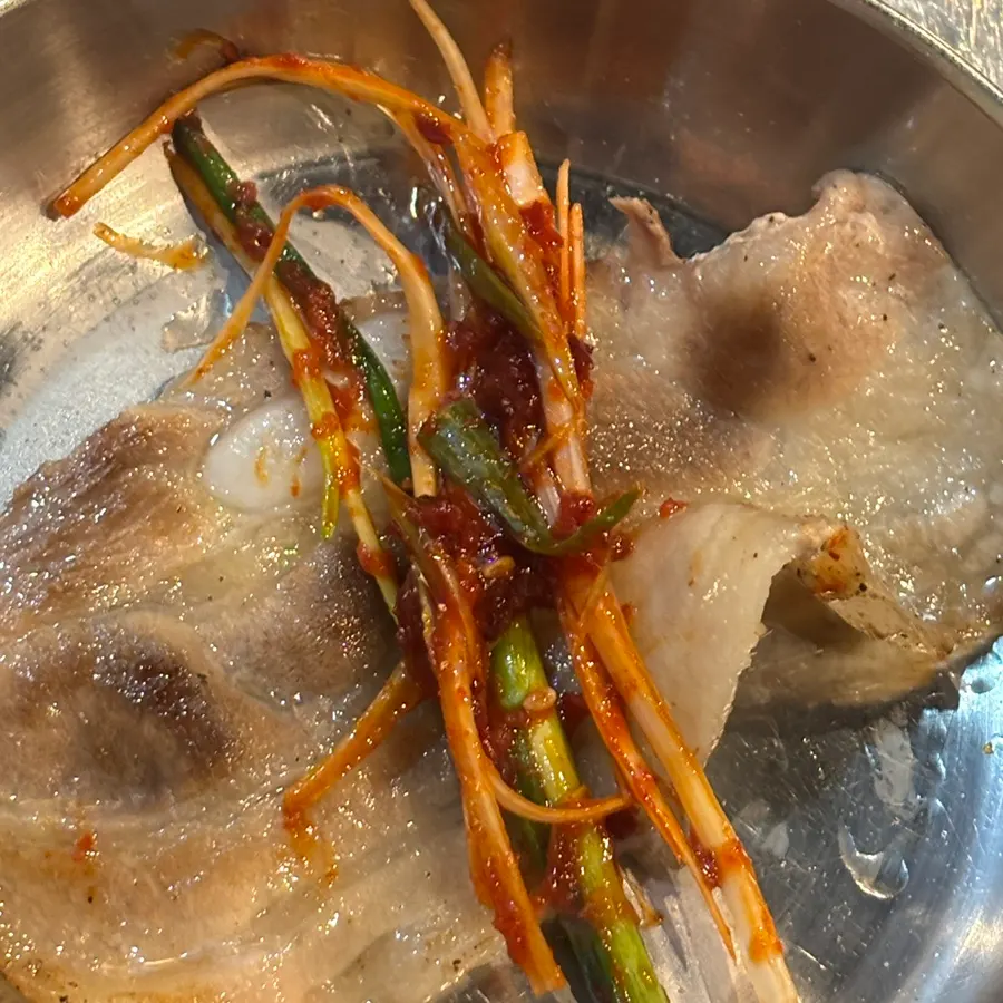 Cold pork belly and scallion salad being grilled