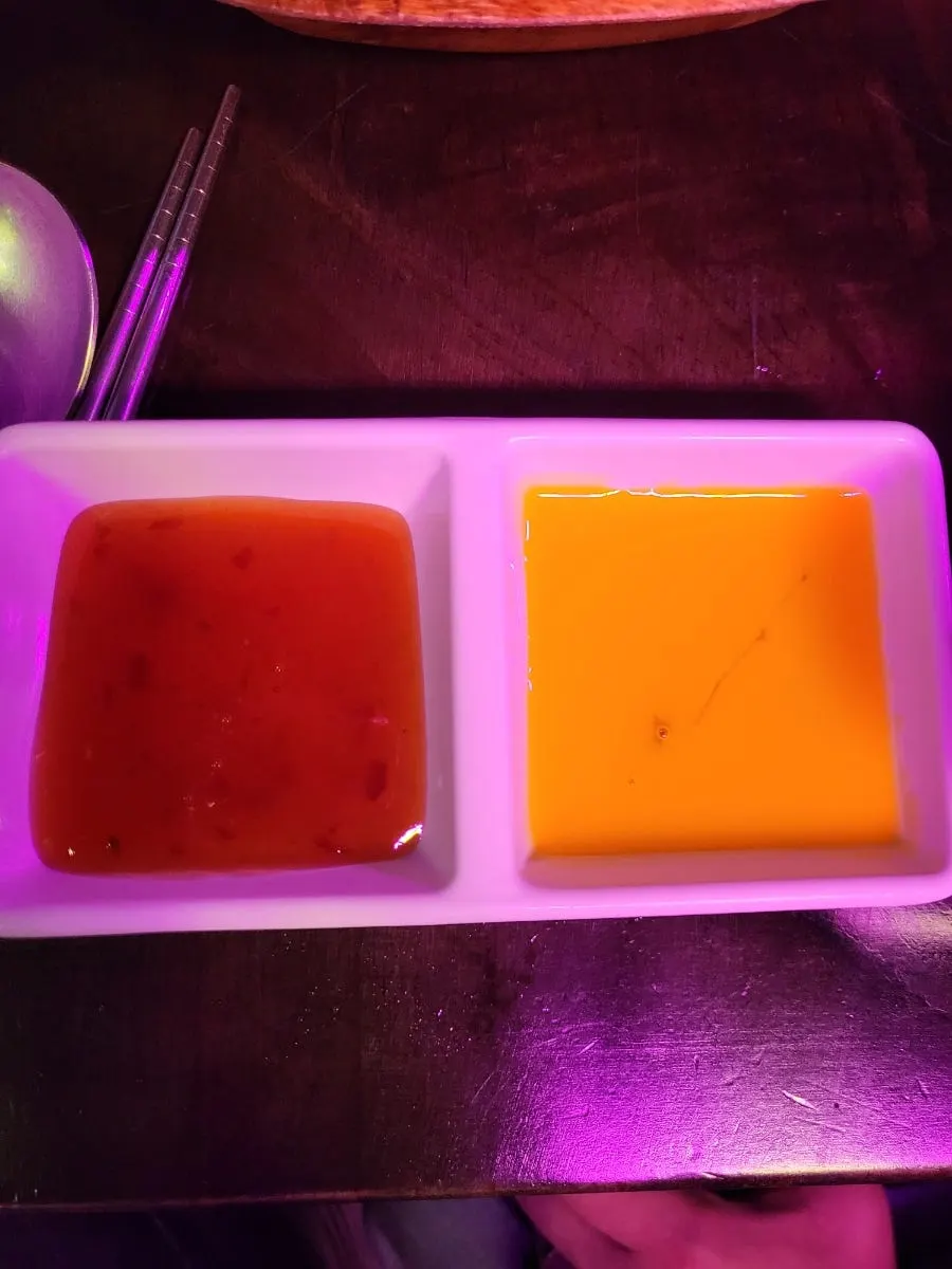 Chili sauce and raw egg yolk served alongside the sukiyaki