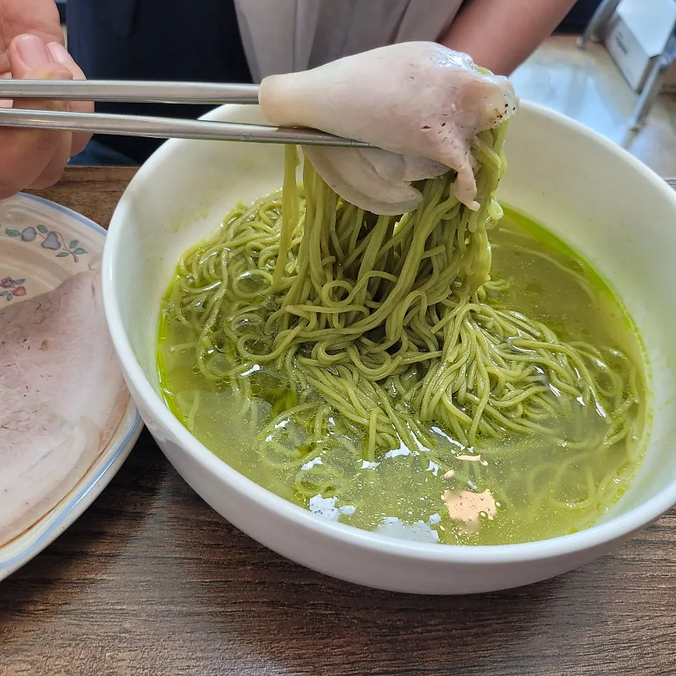 A nearly empty bowl of matcha-noodle meat noodles