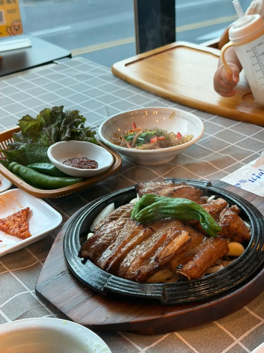 Wood-fired pork galbi on a stone plate lined with onions