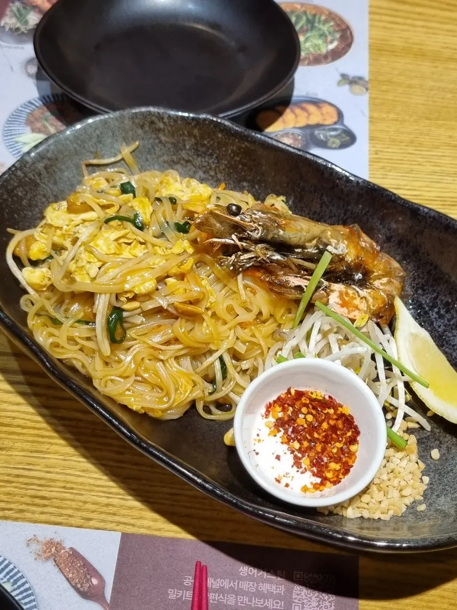 A plate of pad thai topped with giant prawns