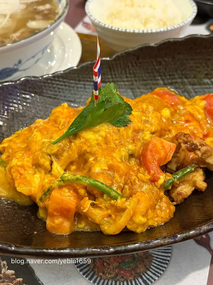 A plate of poo pad pong curry topped with egg and crab