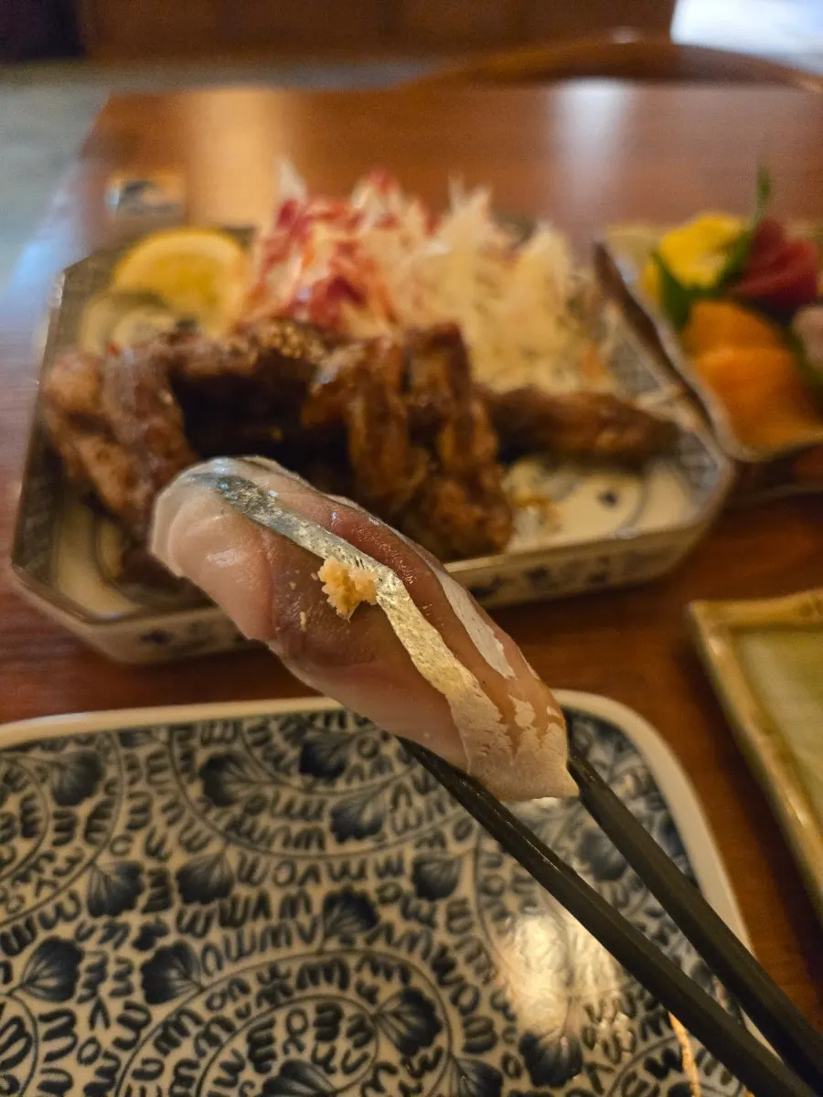 A piece of sashimi held up with chopsticks