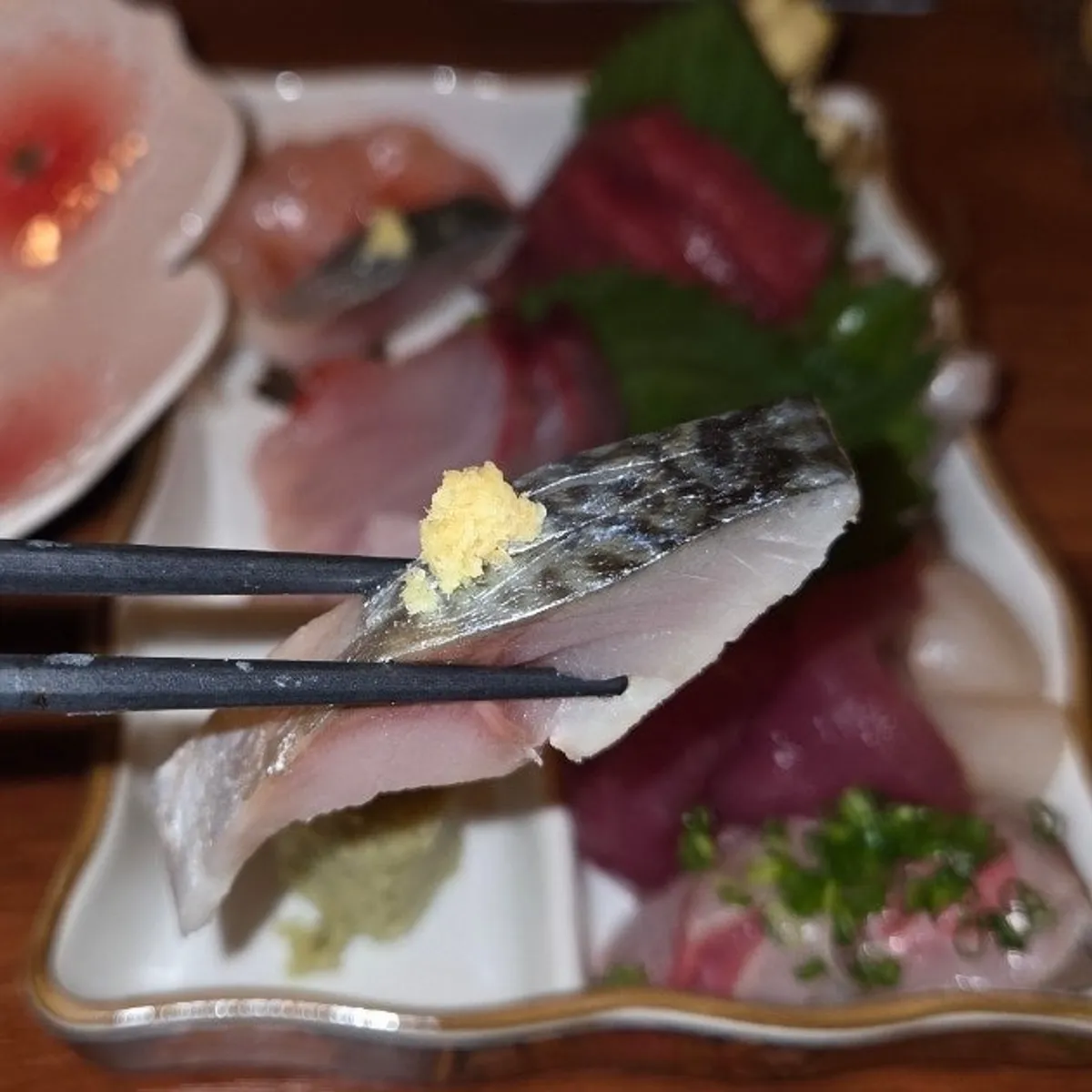 A piece of sashimi lifted with chopsticks