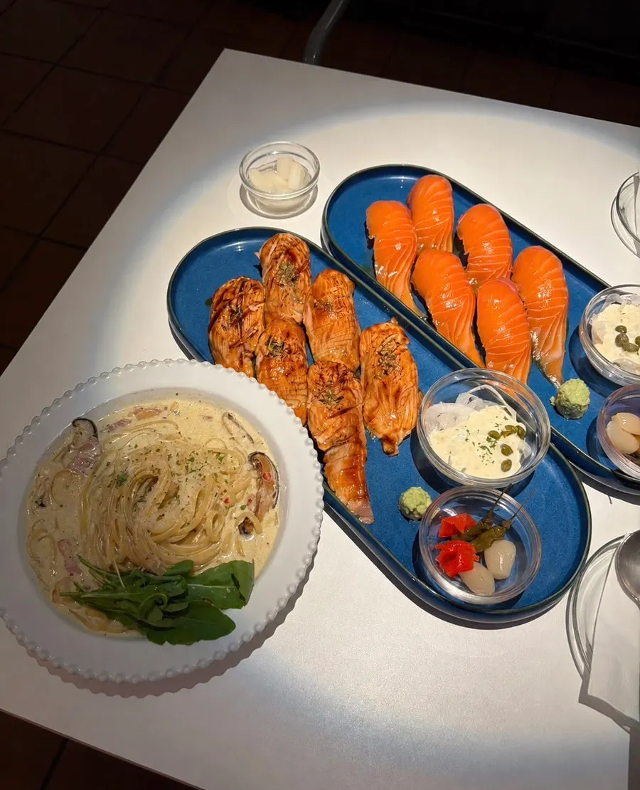 A spread of giant salmon sushi, tataki sushi, and truffle cream pasta