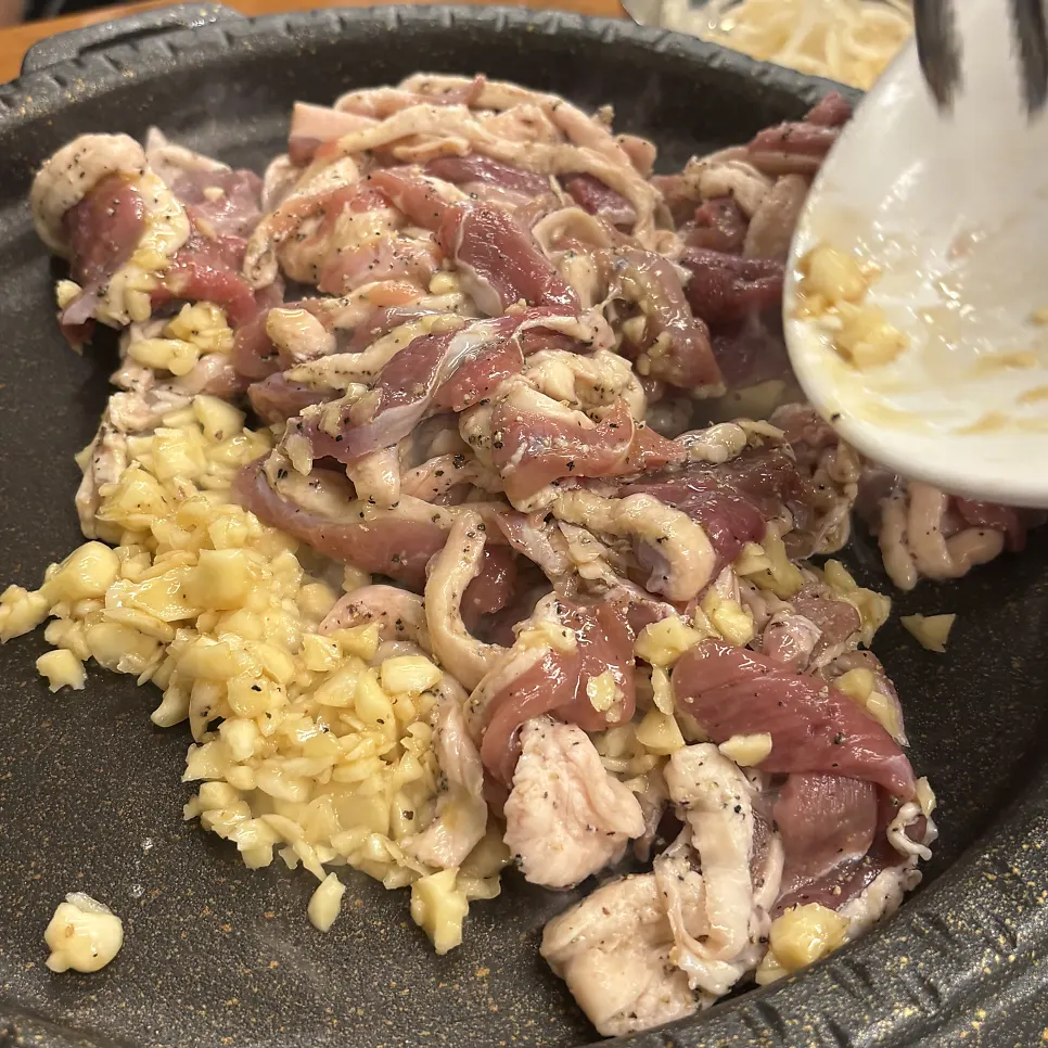 Plate of fresh duck loin topped with a generous amount of garlic