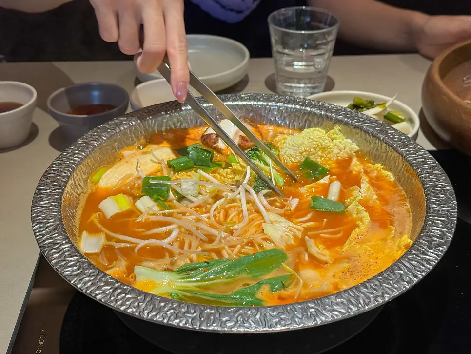 끓는 얼큰버섯 육수에 채소를 넣는 모습