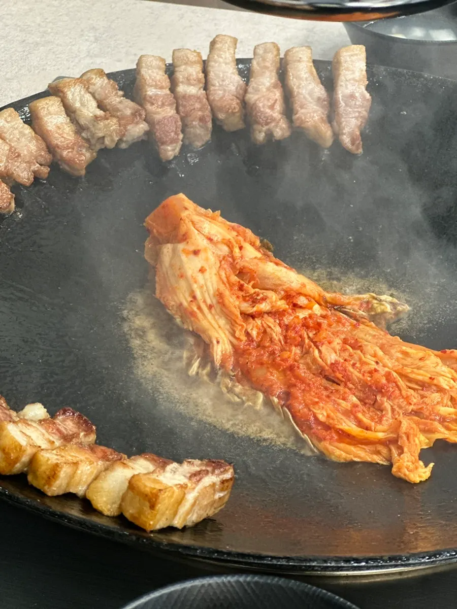 Kimchi added on top of the whole pork belly in the pot lid
