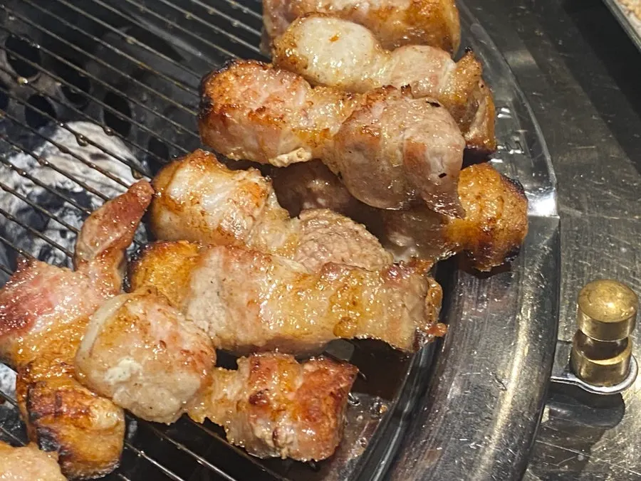 Pork belly turning golden brown over the charcoal fire