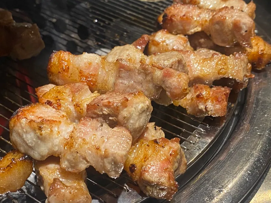 Fully cooked pork belly moved to the side of the grill