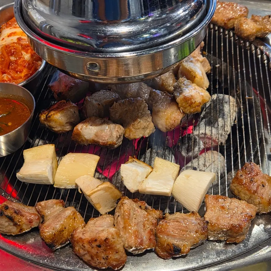 Staff grilling teukmokssal over charcoal as part of the table service