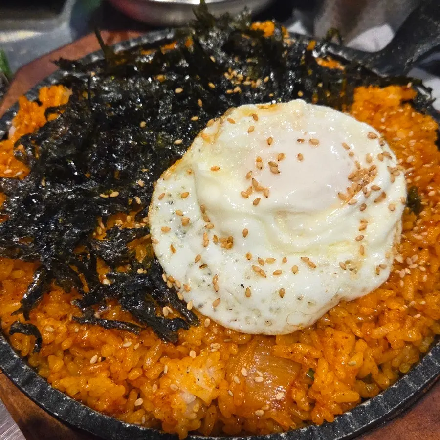 Griddle kimchi fried rice topped with soft-boiled egg and seaweed flakes